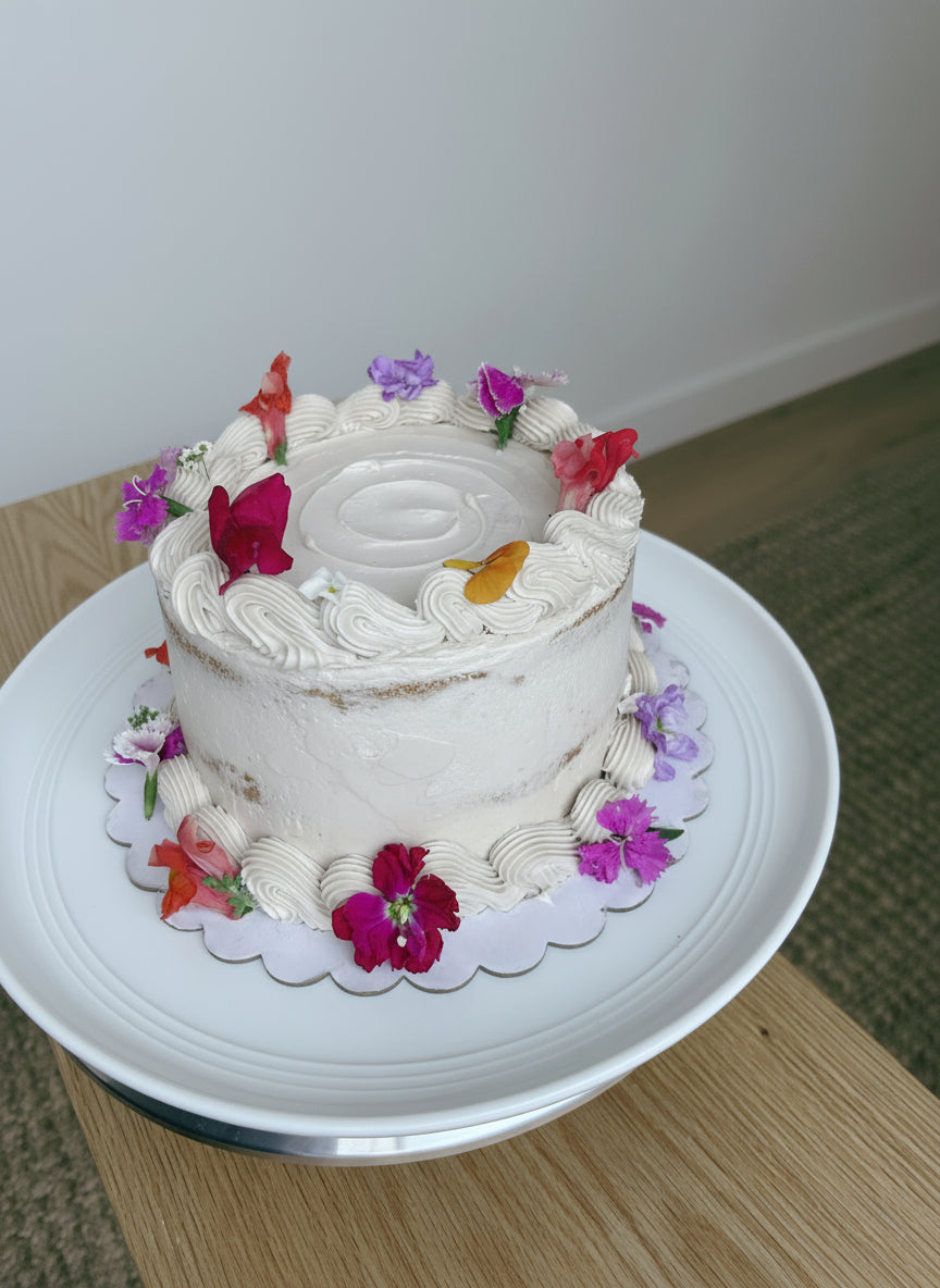 Decorative cake with flowers on a white plate against a plain background